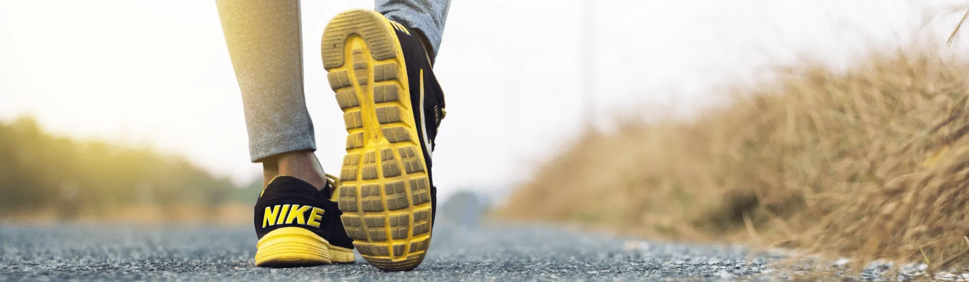 Pessoa caminhando com tênis Nike para corrida no asfalto