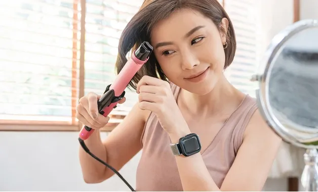 Mulher asiática de cabelo curto modela o cabelo com um babyliss