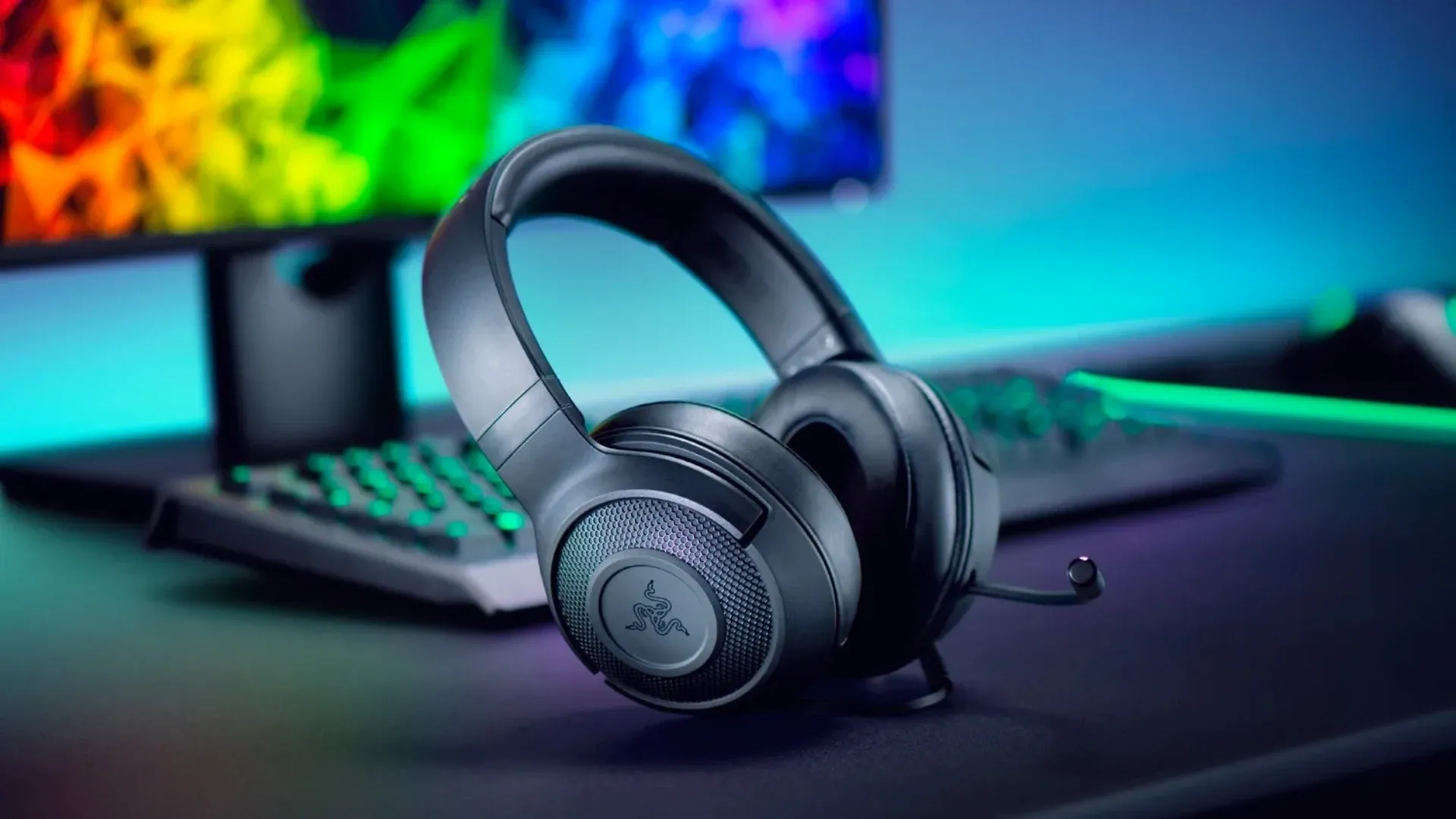 A imagem apresenta um modelo de headset Razer Kraken disposto sobre uma mesa, enquanto outros produtos da Razer estão desfocados ao fundo
