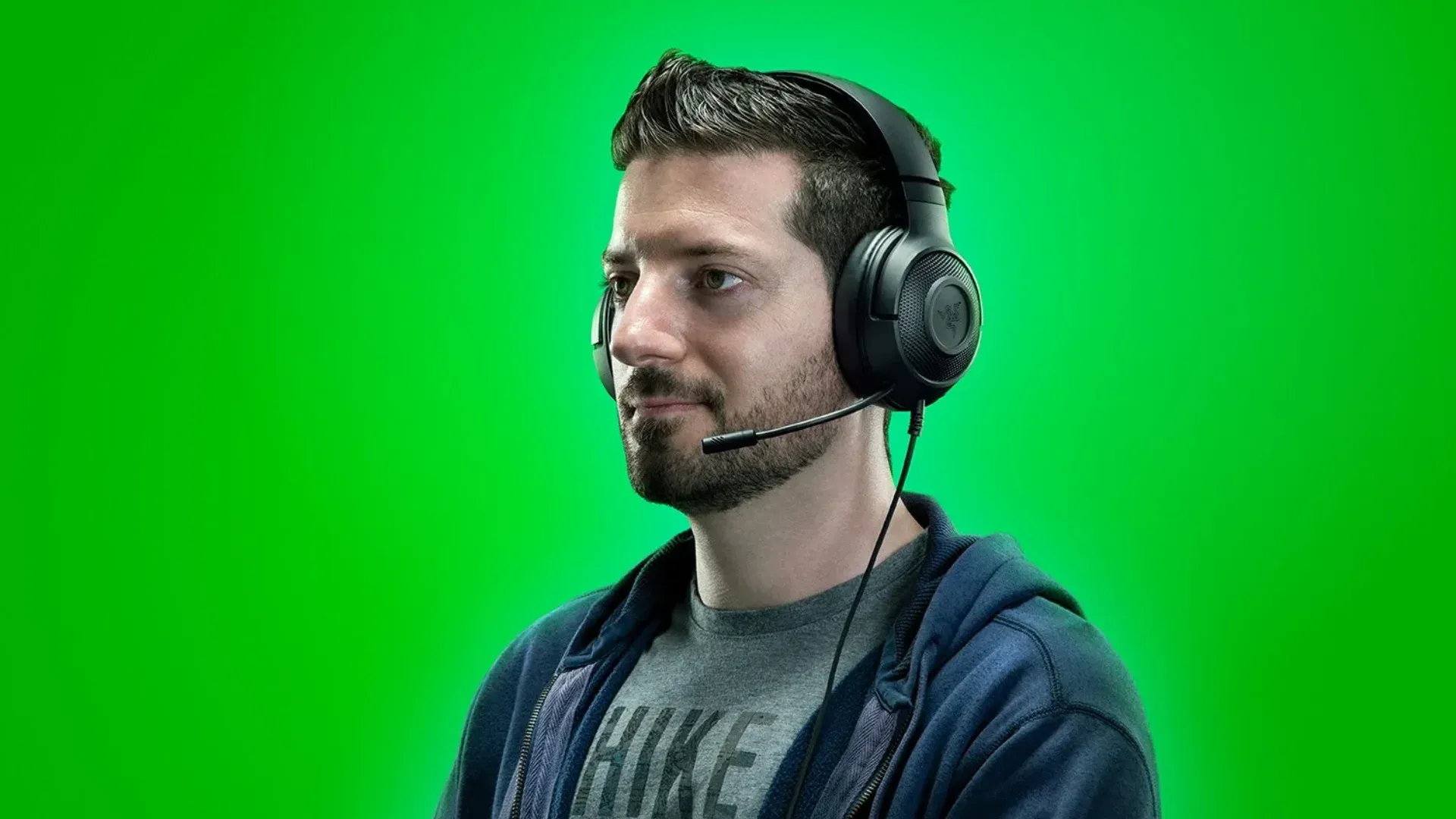 A imagem mostra um modelo utilizando um headset Razer Kraken, com o fundo completamente verde.