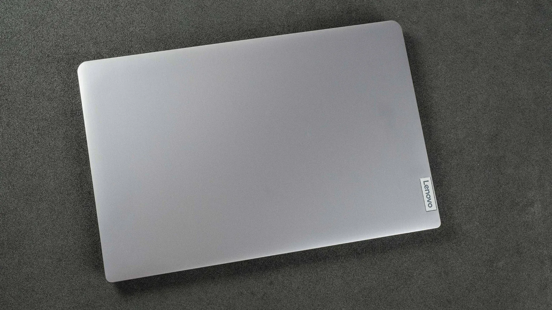 Notebook Lenovo IdeaPad 3 82MFS00100 visto de cima, fechado, todo prateado com um selo escrito 'Lenovo' no canto inferior direito