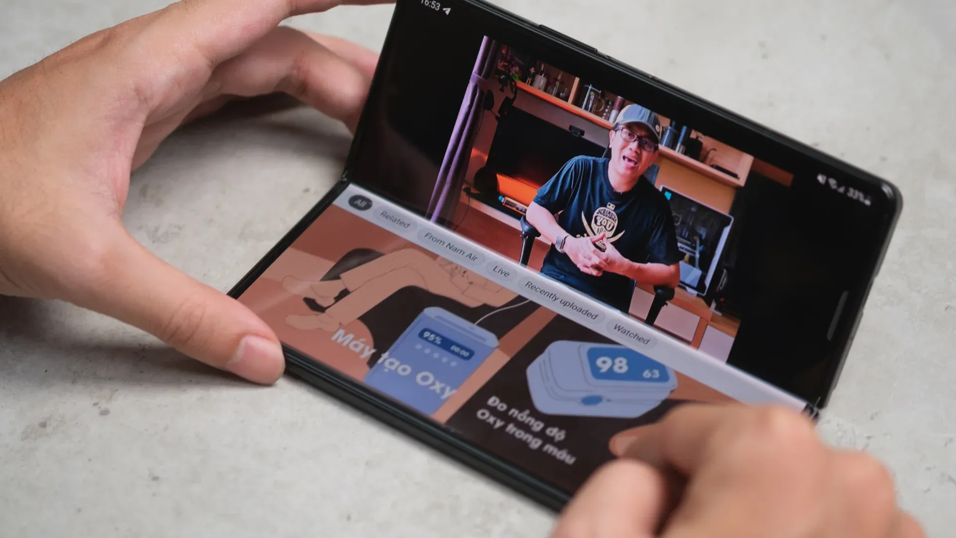 Um homem aparece em uma tela do Galaxy Z Fold 3 enquanto duas mãos seguram o aparelho sobre uma superfície