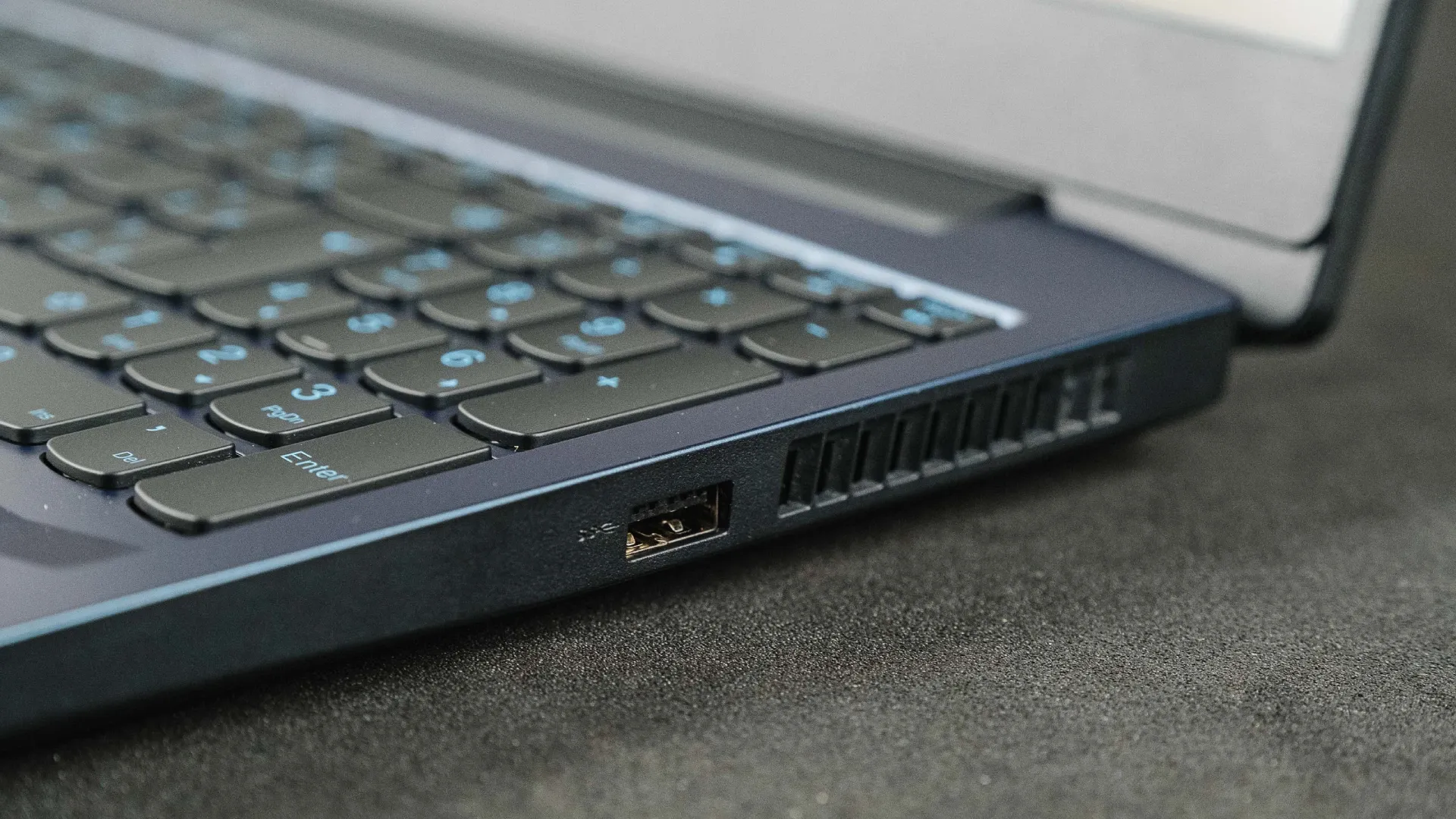 Imagem do lado direito do IdeaPad Gaming 3i, mostrando uma entrada USB e a saída da ventilação