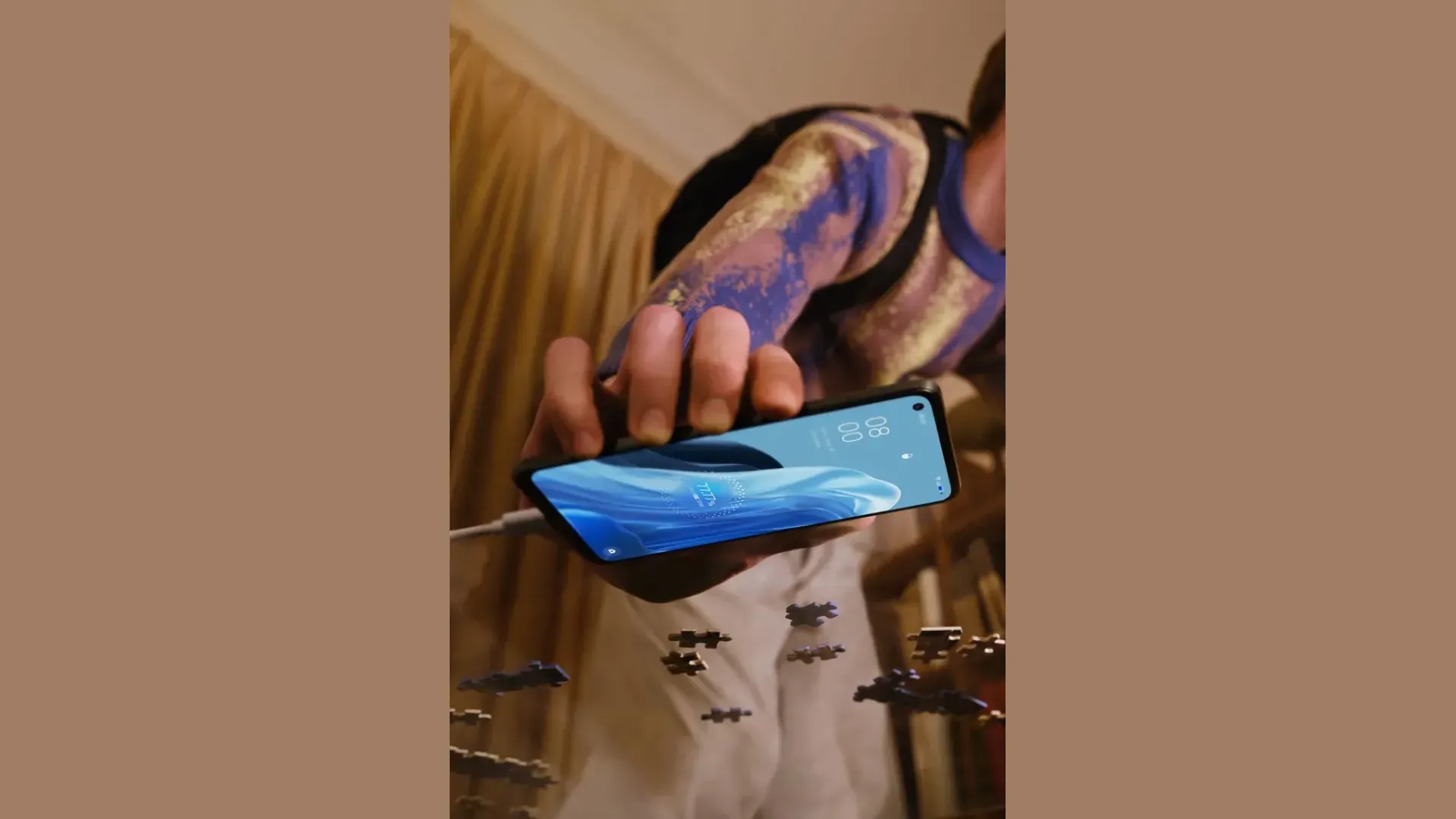 Homem segurando celular OPPO Reno 7 carregando a bateria ao lado de peças de quebra-cabeça
