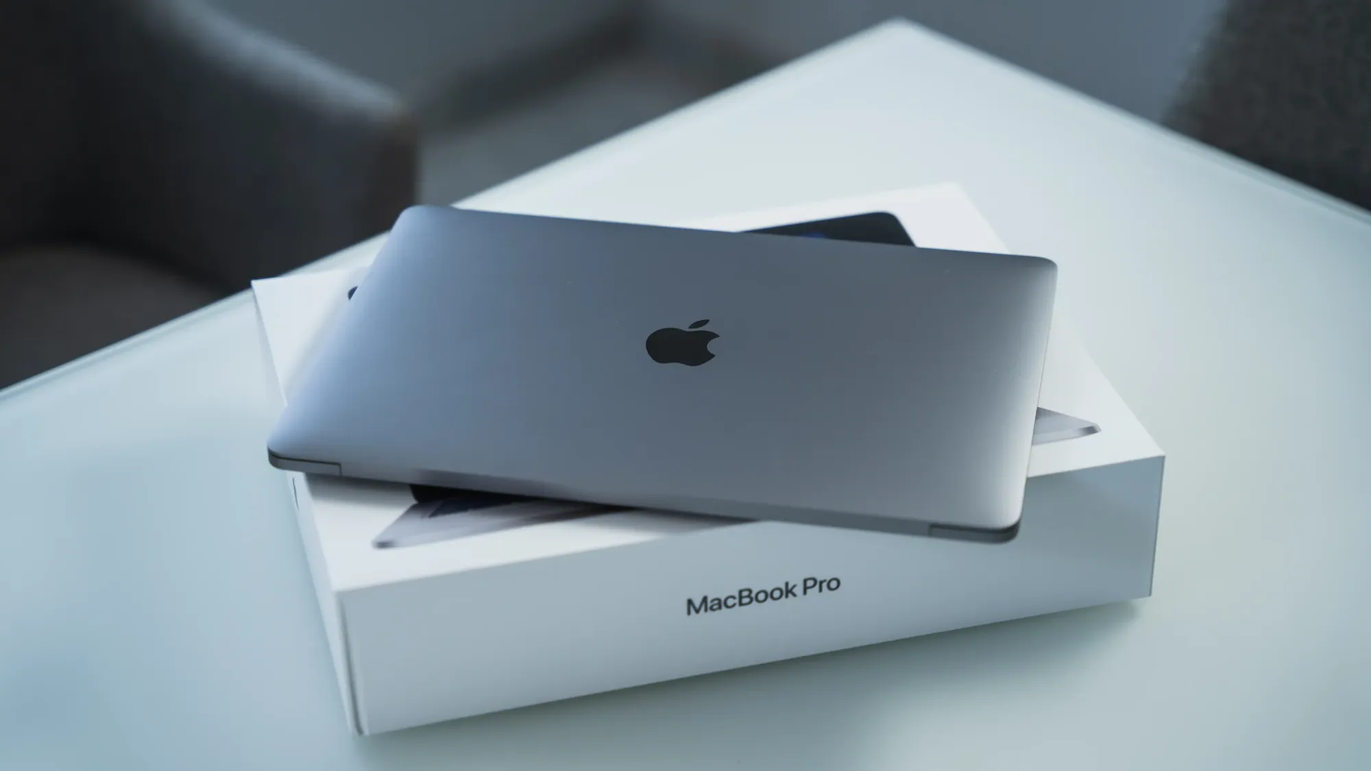 Um MacBook Pro 2020 fechado sobre sua caixa em cima de uma mesa.