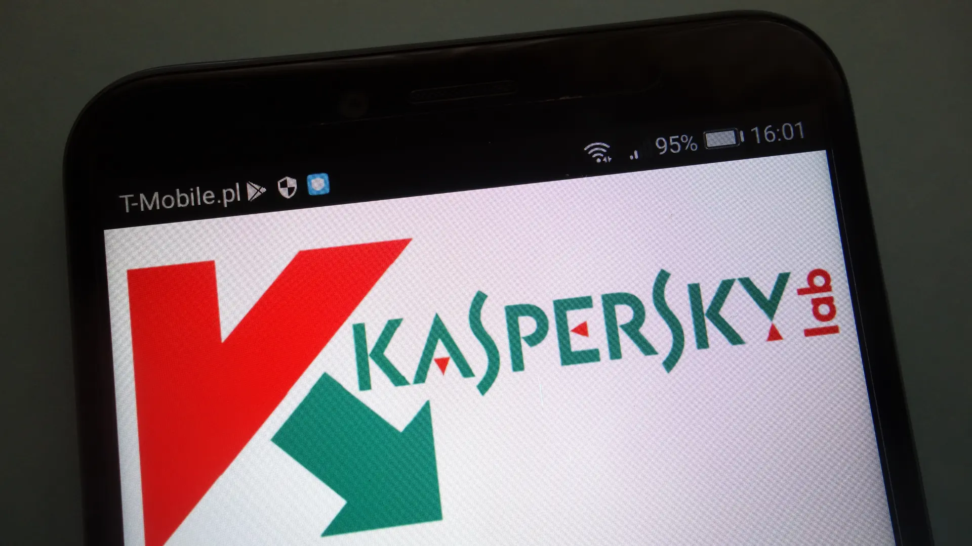 Um celular sobre uma superfície marrom com o logo da Kaspersky aparecendo na tela.