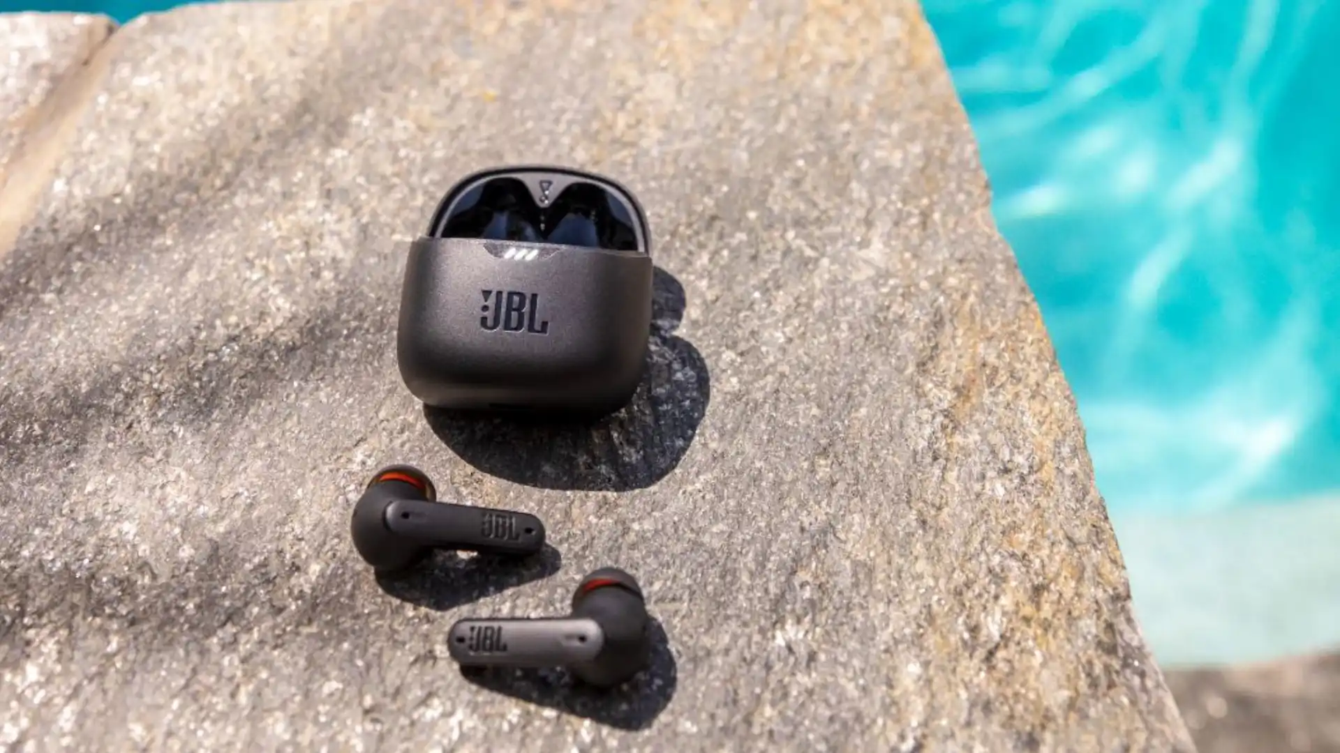 Fones de ouvido JBL Tune Flex na beira de uma piscina.