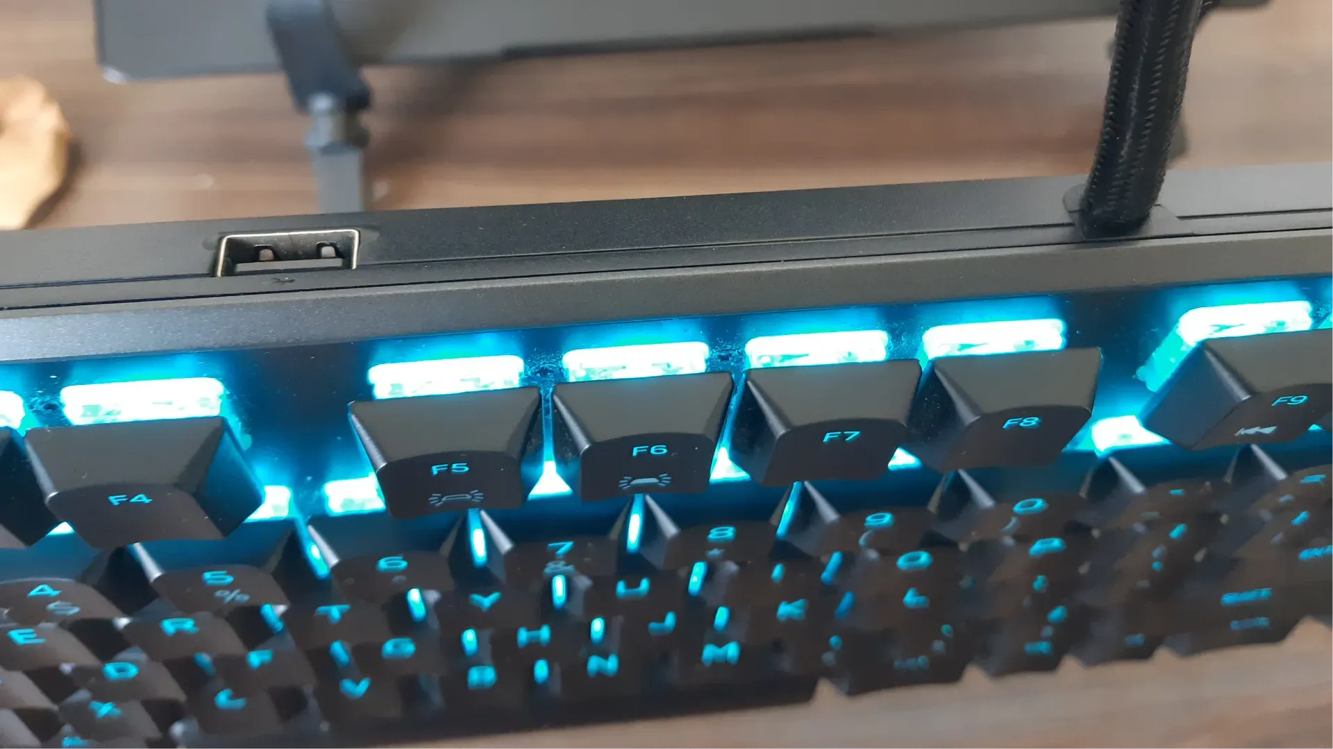 Foto do teclado com destaque para o fio e a porta USB que ficam na parte superior e são as únicas opções de conexão do Alienware AW510K
