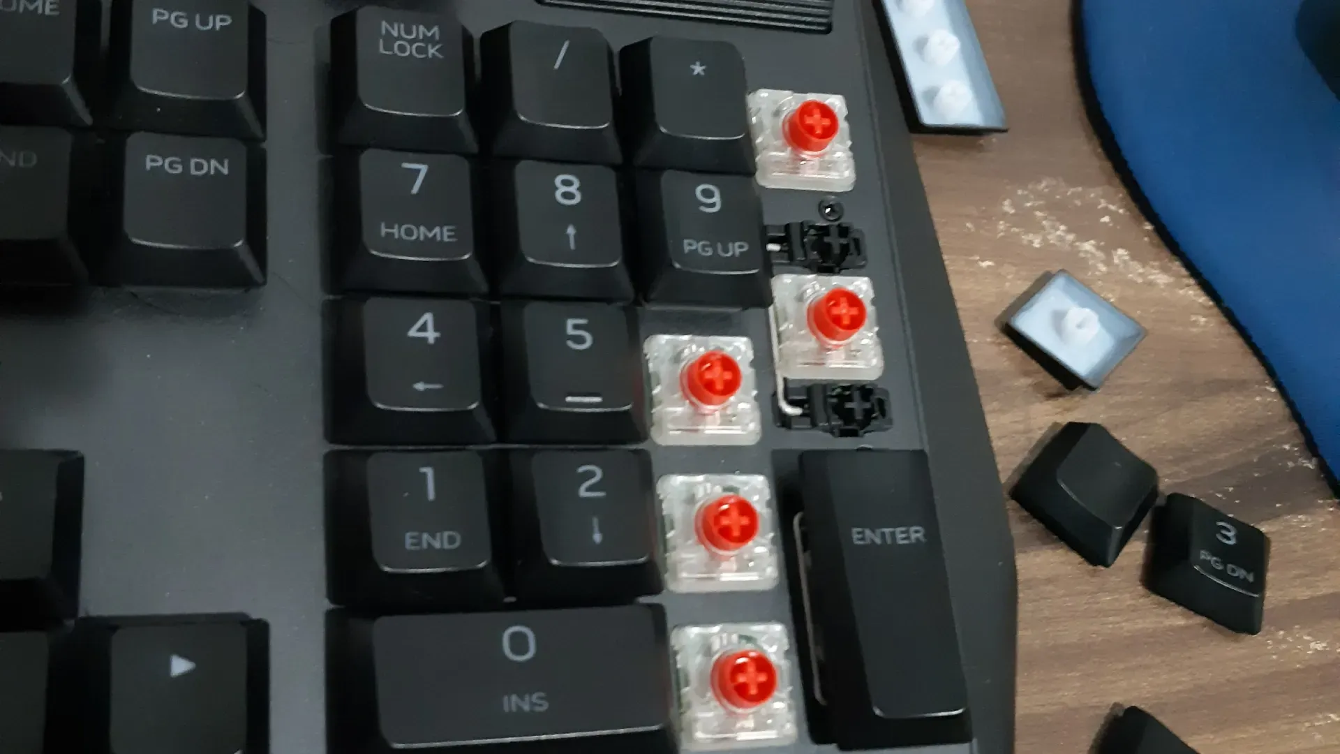 Foto do teclado Alienware AW510K com destaque para o teclado numérico, que está com algumas teclas removidas ao lado, mostrando o interruptor vermelho que fica abaixo da tecla