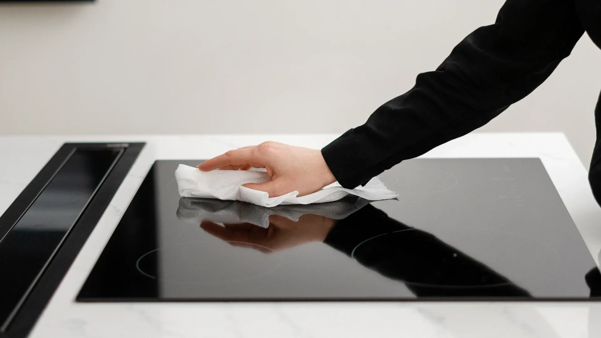 fogão moderno com mesa de vidro sendo limpo com pano