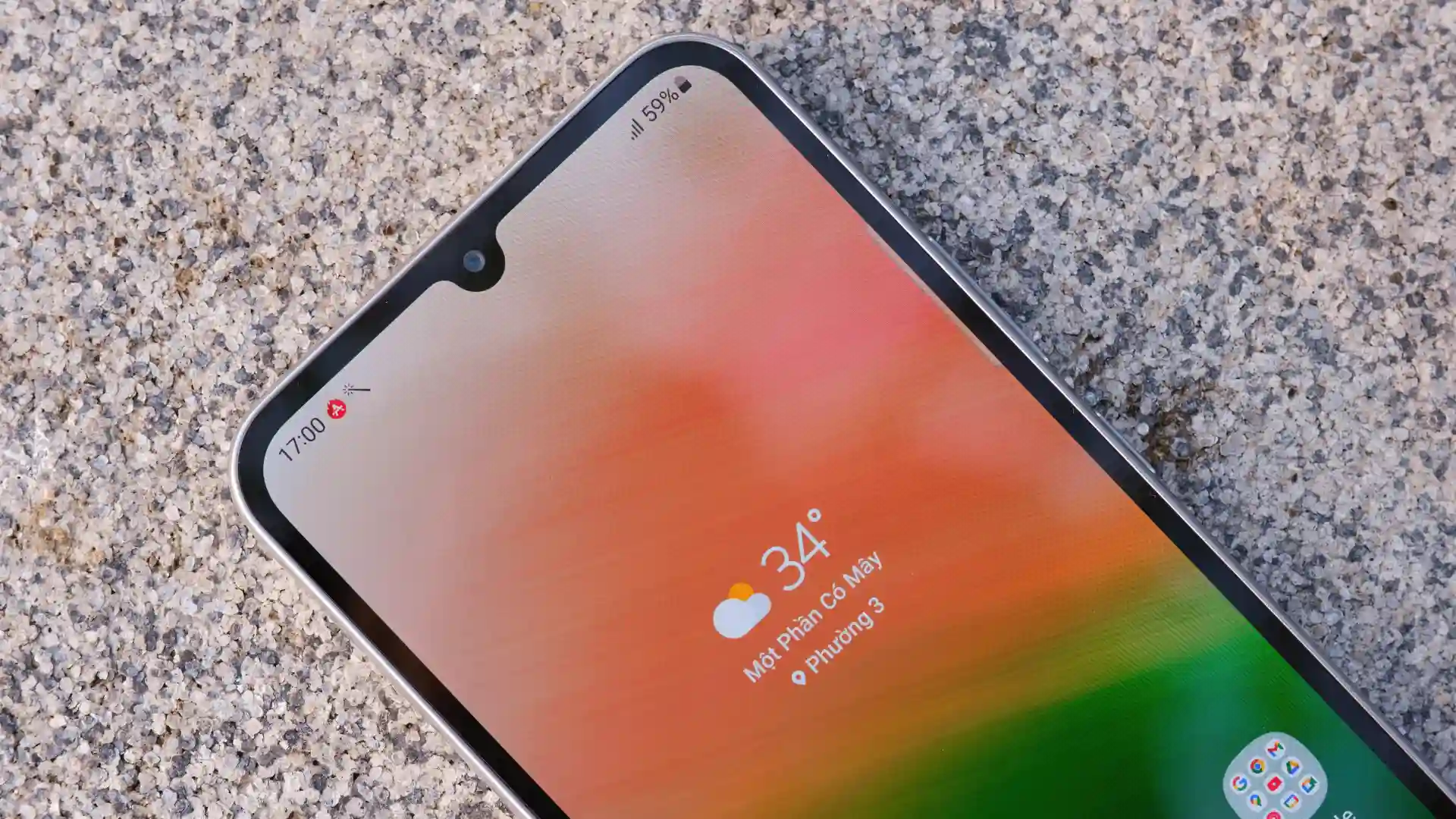 Um celular Galaxy A34 está com a tela ligada sobre uma superfície granulada