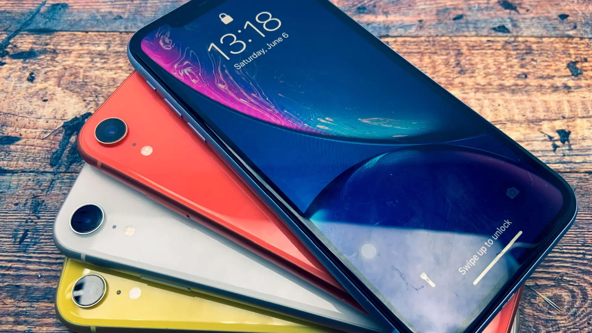 Diversas opções de cores de iPhone XR usado sobre mesa de madeira.