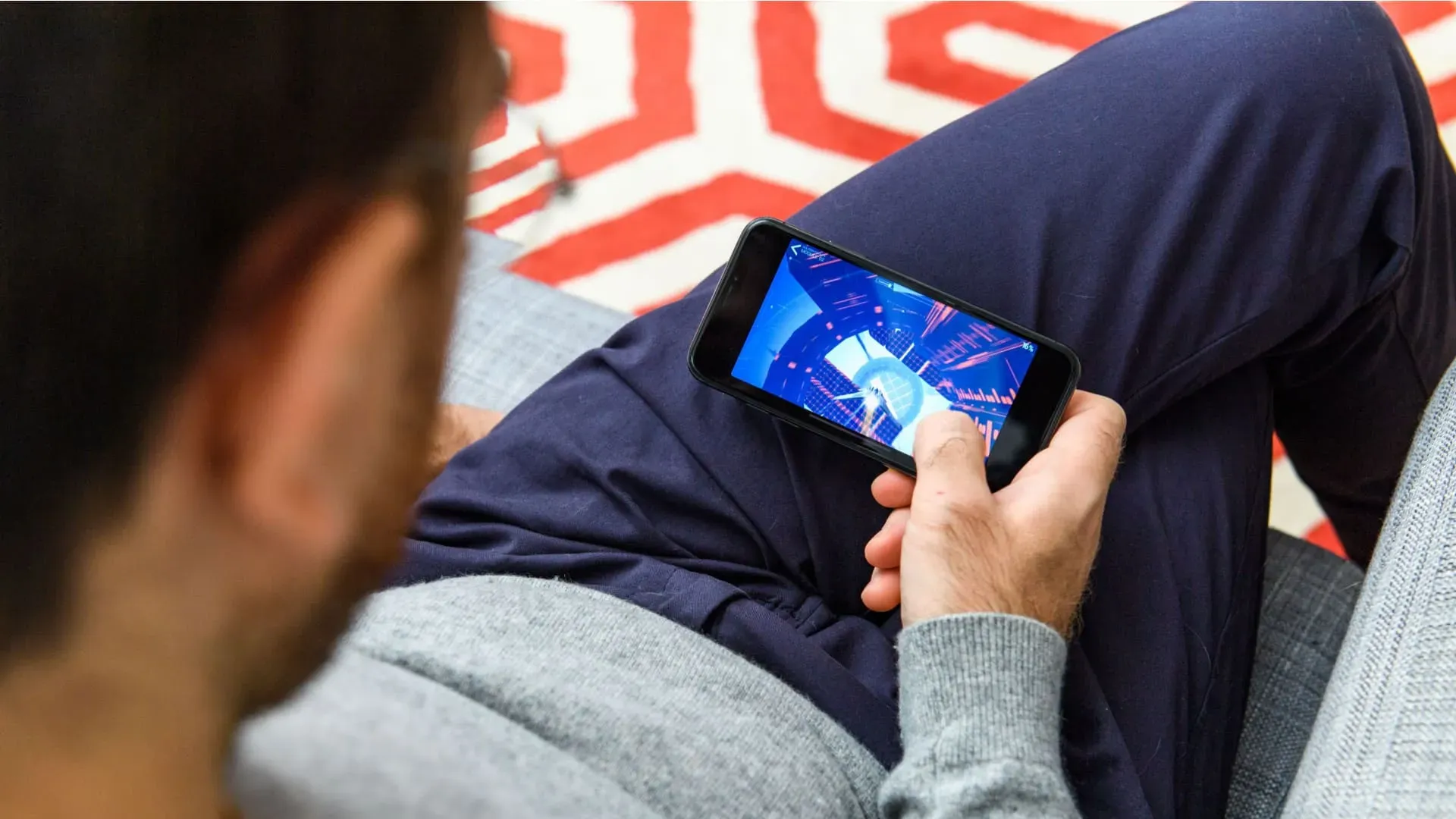 Homem sentado em sofá jogando com o seu iPhone XR usado