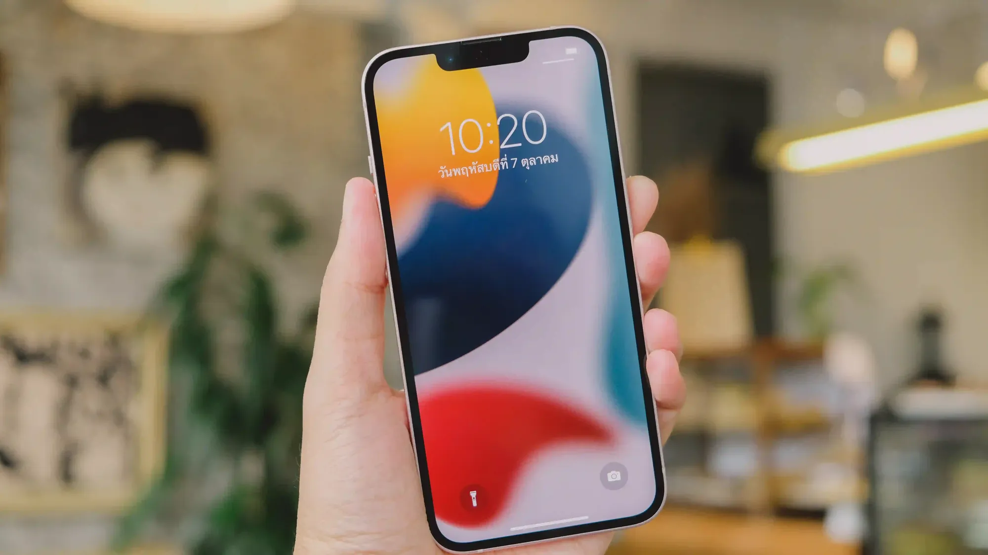 Uma pessoa segura um telefone iPhone com uma das mãos enquanto mostra a tela que está ligada
