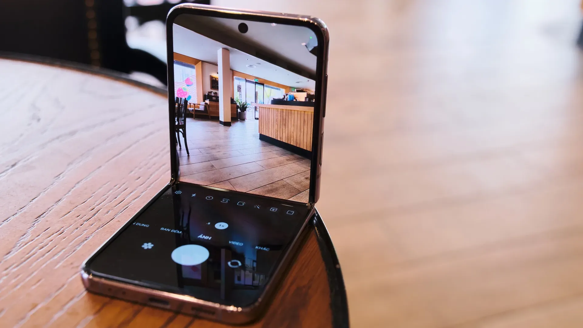 Um celular modelo Galaxy Z Flip 4 está sobre uma mesa de madeira e entreaberto