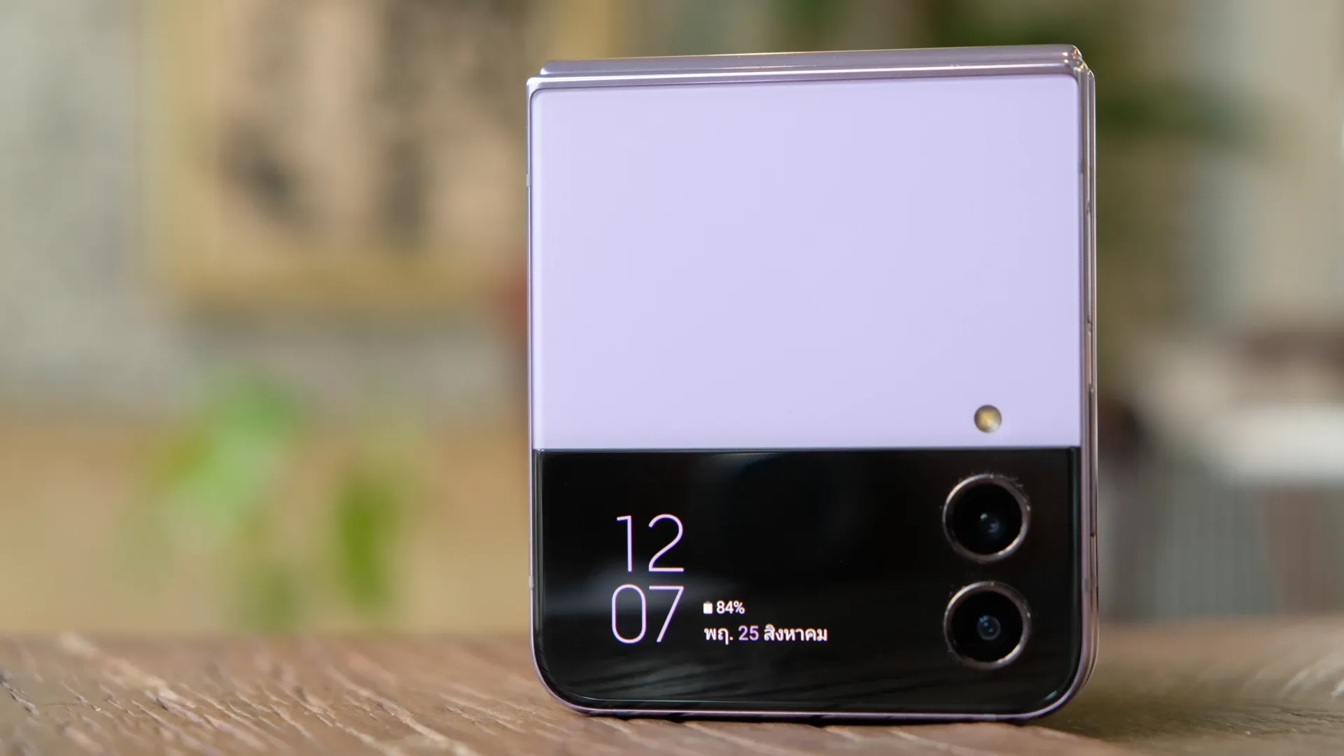 Um celular dobrável da Samsung de cor roxa está dobrado sobre uma mesa de madeira