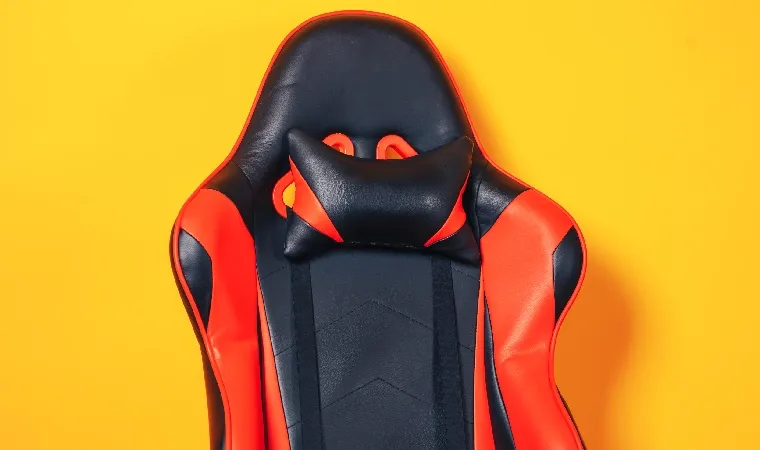 Cadeira gamer vermelha e preta com fundo amarelo virada de frente 