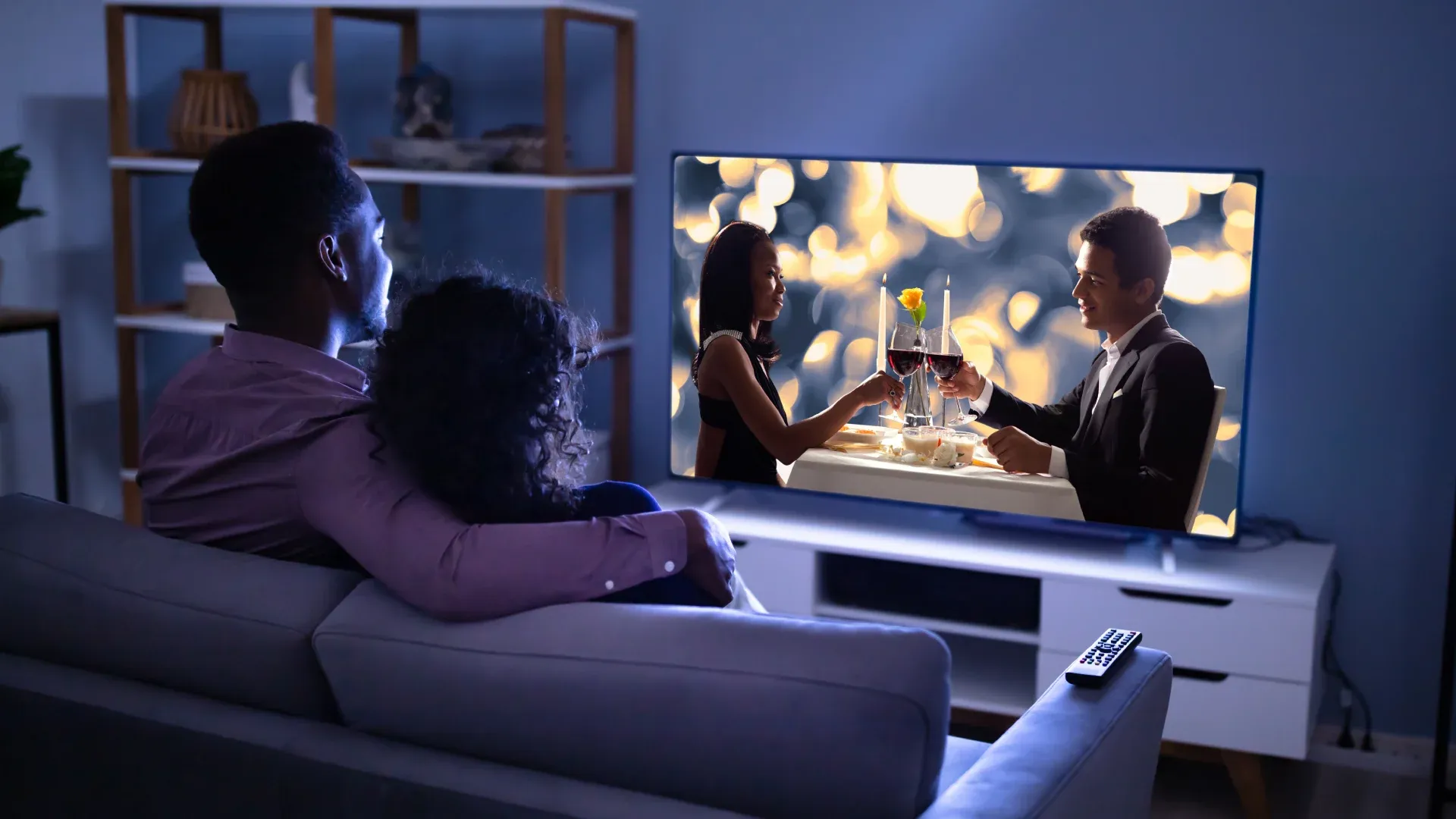 Casal sentado no sofá assistindo televisão