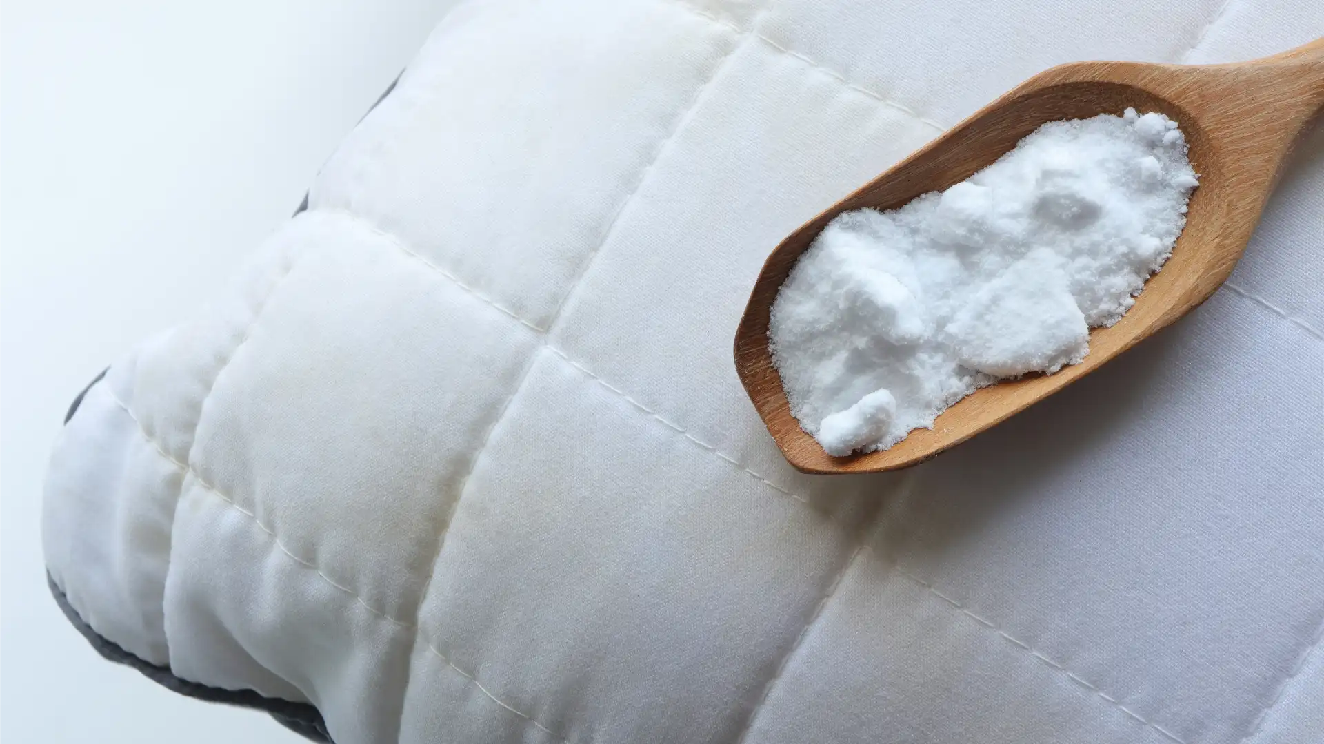Bicarbonato de sódio em uma colher de madeira, sendo colocado em um colchão sujo