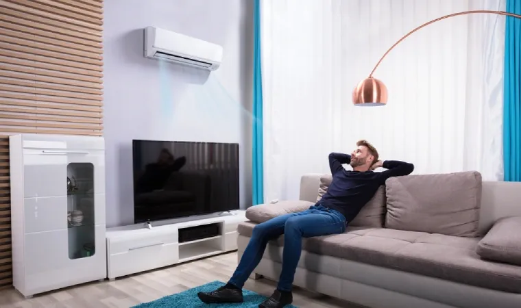 Homem no sofá da sala se refrescando com ar condicionado