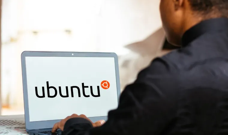 Homem usando um notebook onde na tela aparece a imagem do Linux Ubuntu