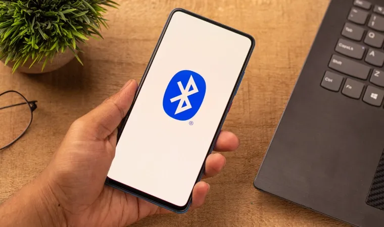 Pessoa segurando um celular com ícone do Bluetooth na tela