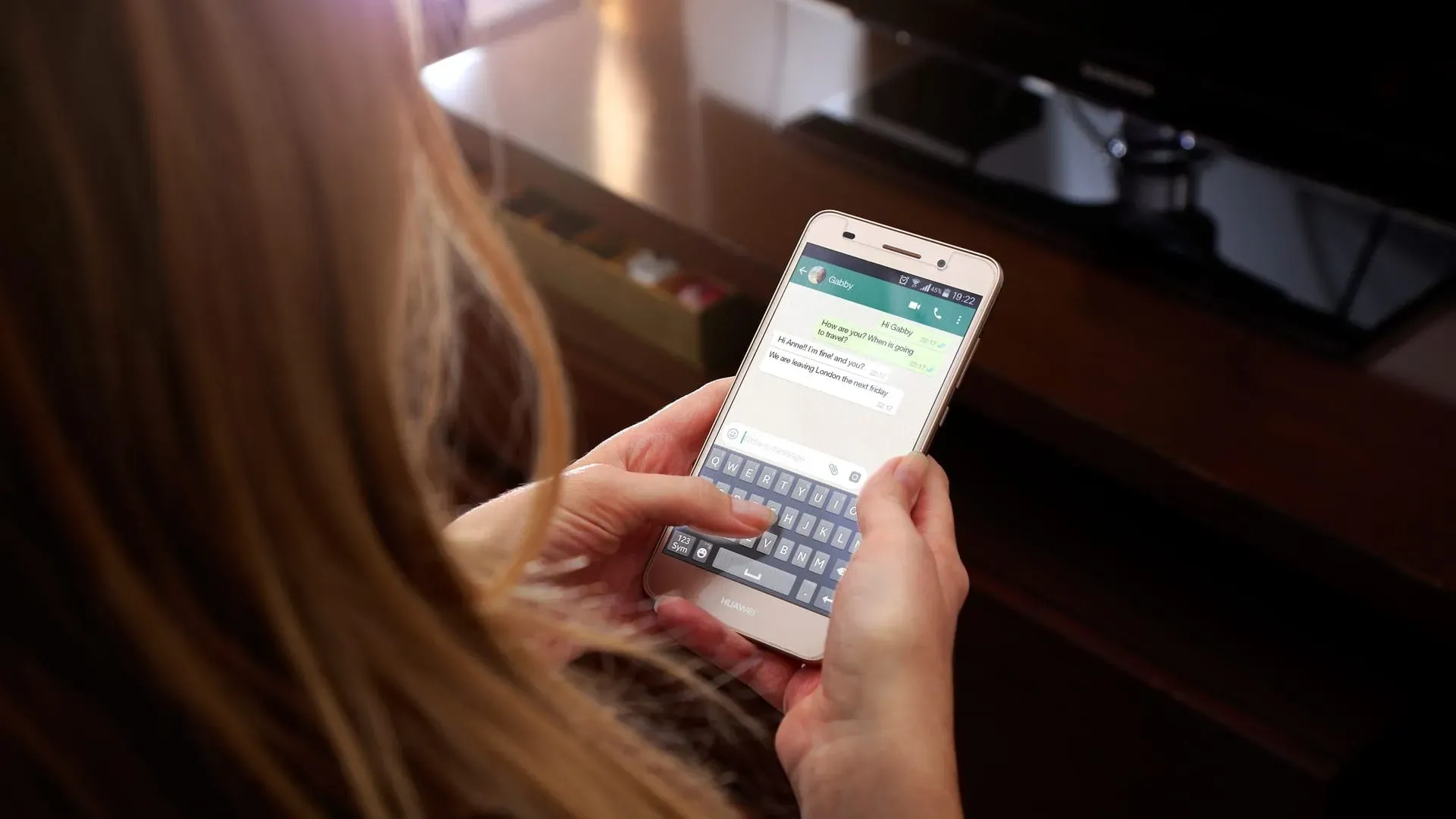 Imagem de uma mulher digitando em um celular, em uma tela do WhatsApp aberta
