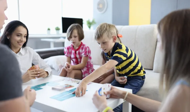 Pais e filhos se divertem nem uma sala durante jogo de cartas