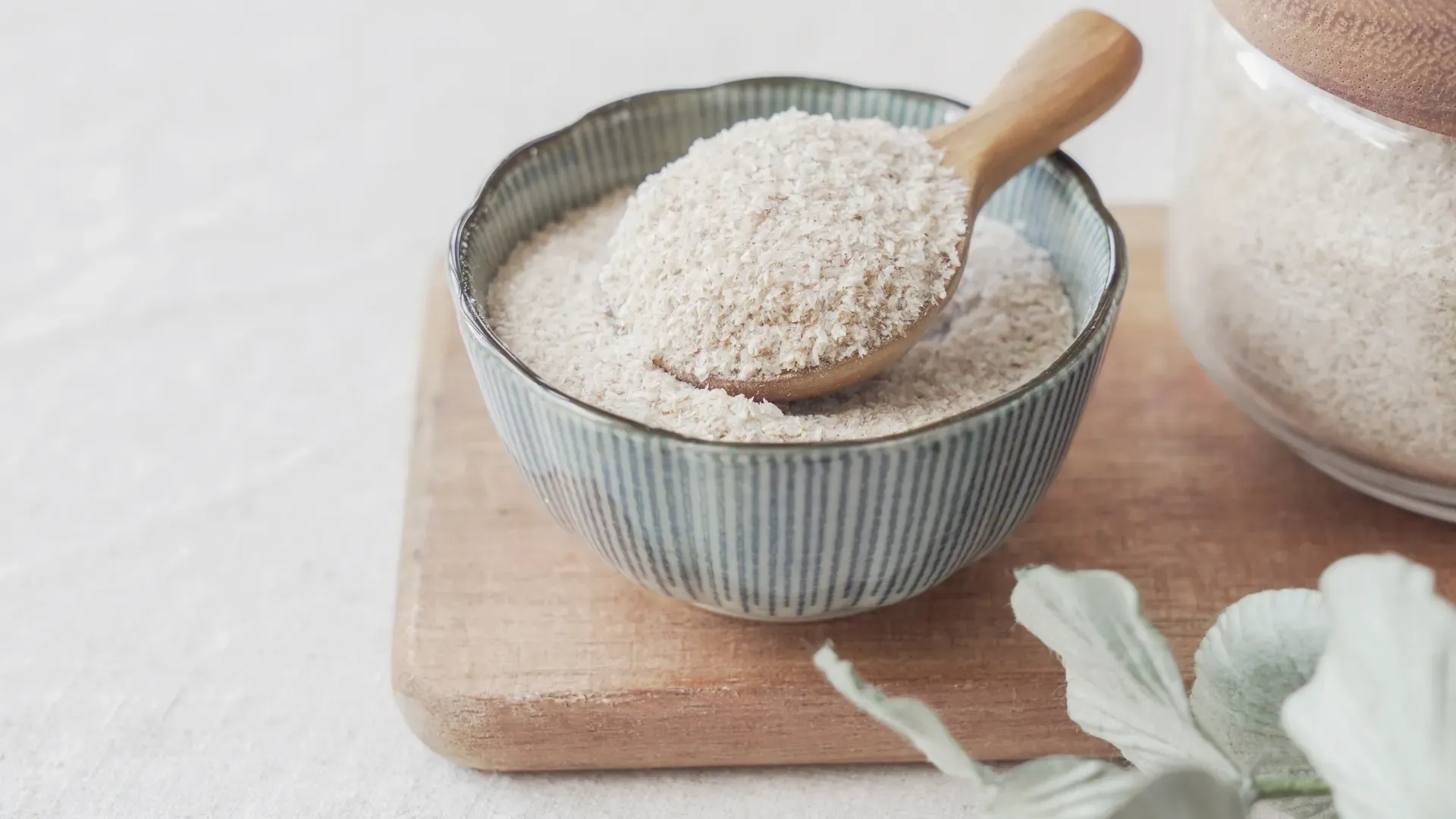 Casca de psyllium em colher de madeira e tigela em placa de madeira