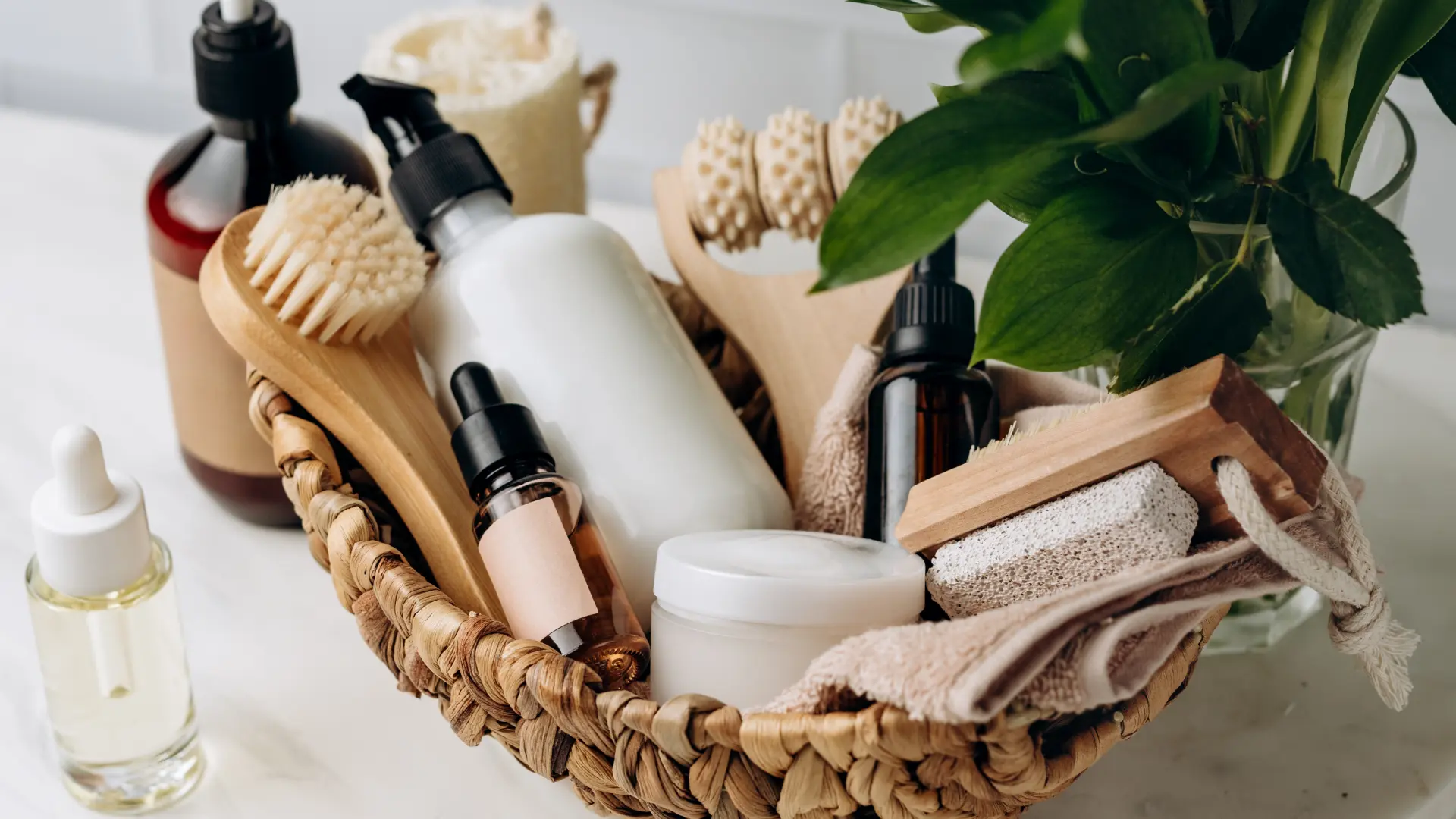 Cesta de vime apoiada em pia branca cheia de itens para relaxamento no banho