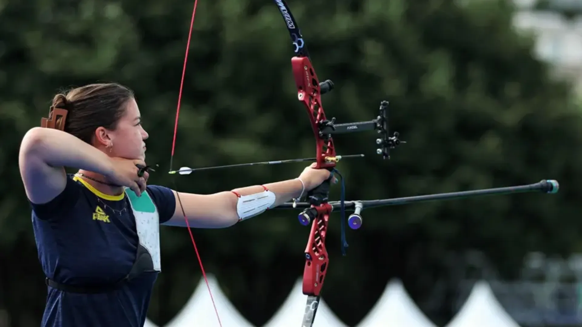 Mulher branca ao ar livre praticando tiro ao arco