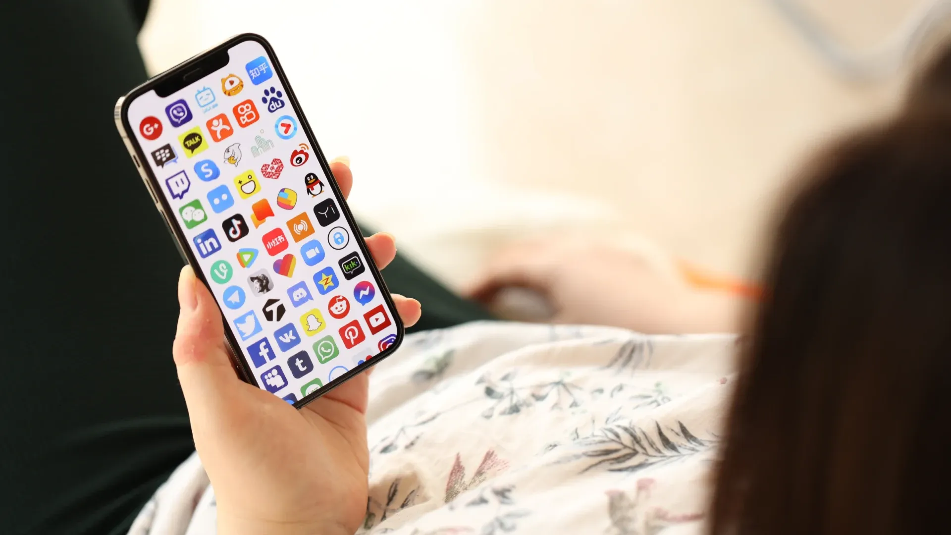 Mulher segurando um iPhone com muitos aplicativos abertos