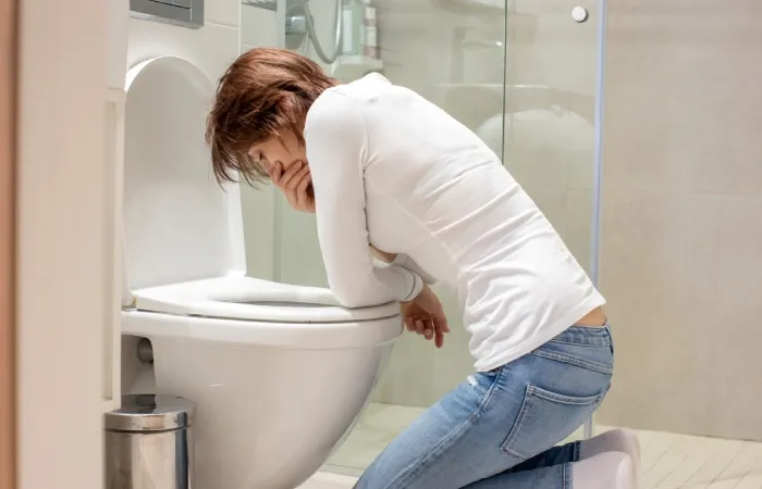 Imagem de uma pessoa com náuseas prestes a vomitar em um vaso sanitário