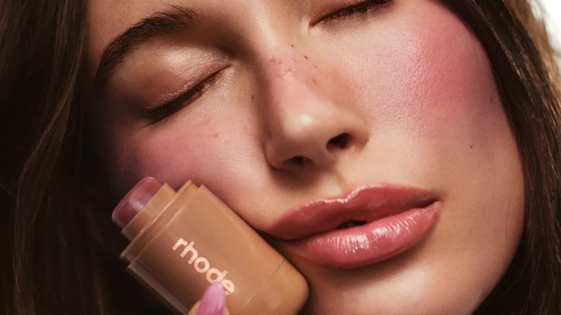 Hailey Bieber segurando o Pocket Blush da Rhode Skin perto de seu rosto