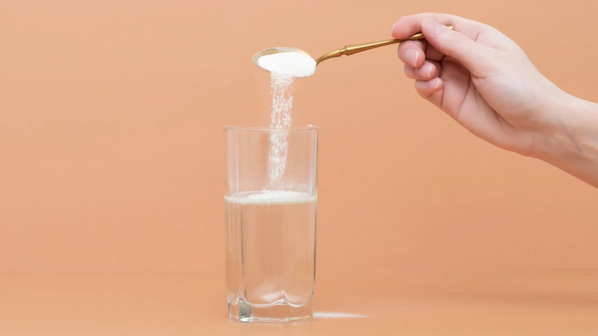 Fundo laranja e um copo com água recebendo uma colher de pó branco