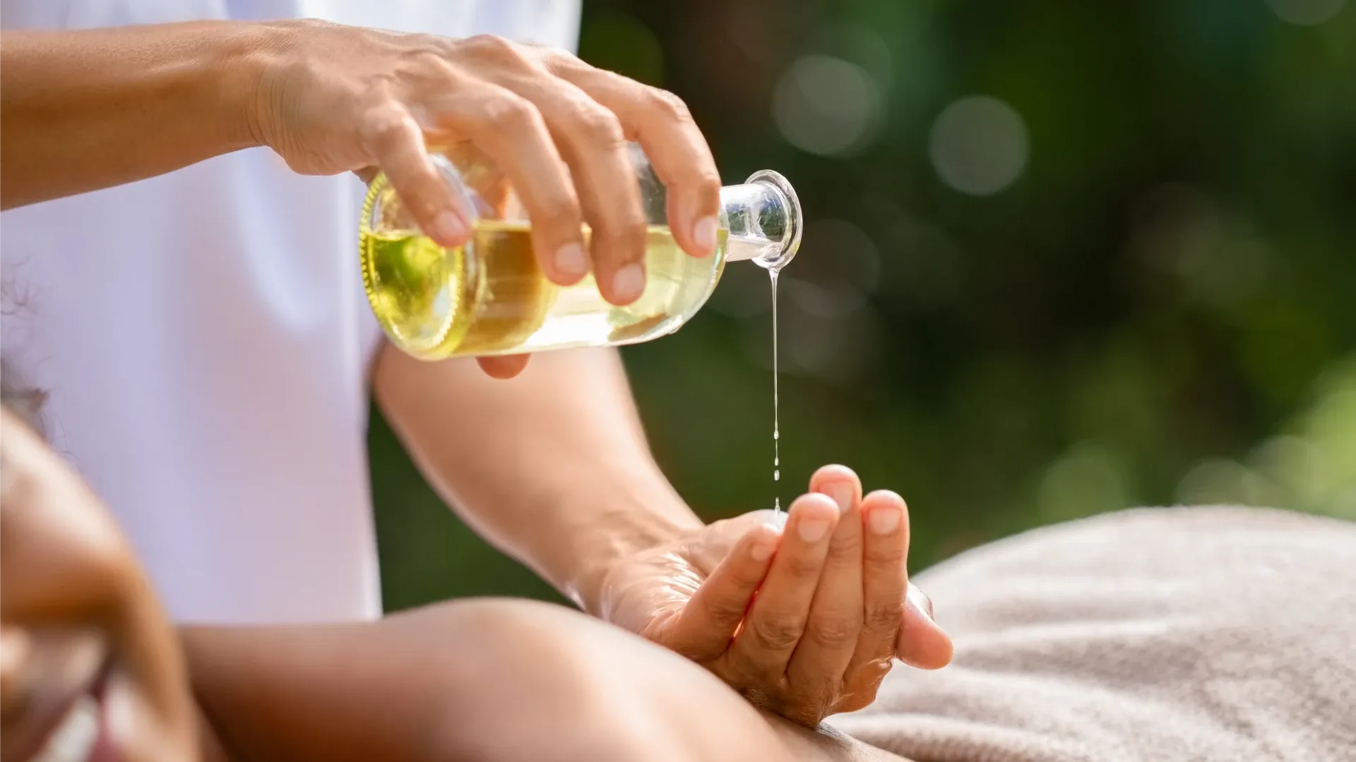 Homem despejando óleo de banho em suas mãos, prestes a massagear uma mulher