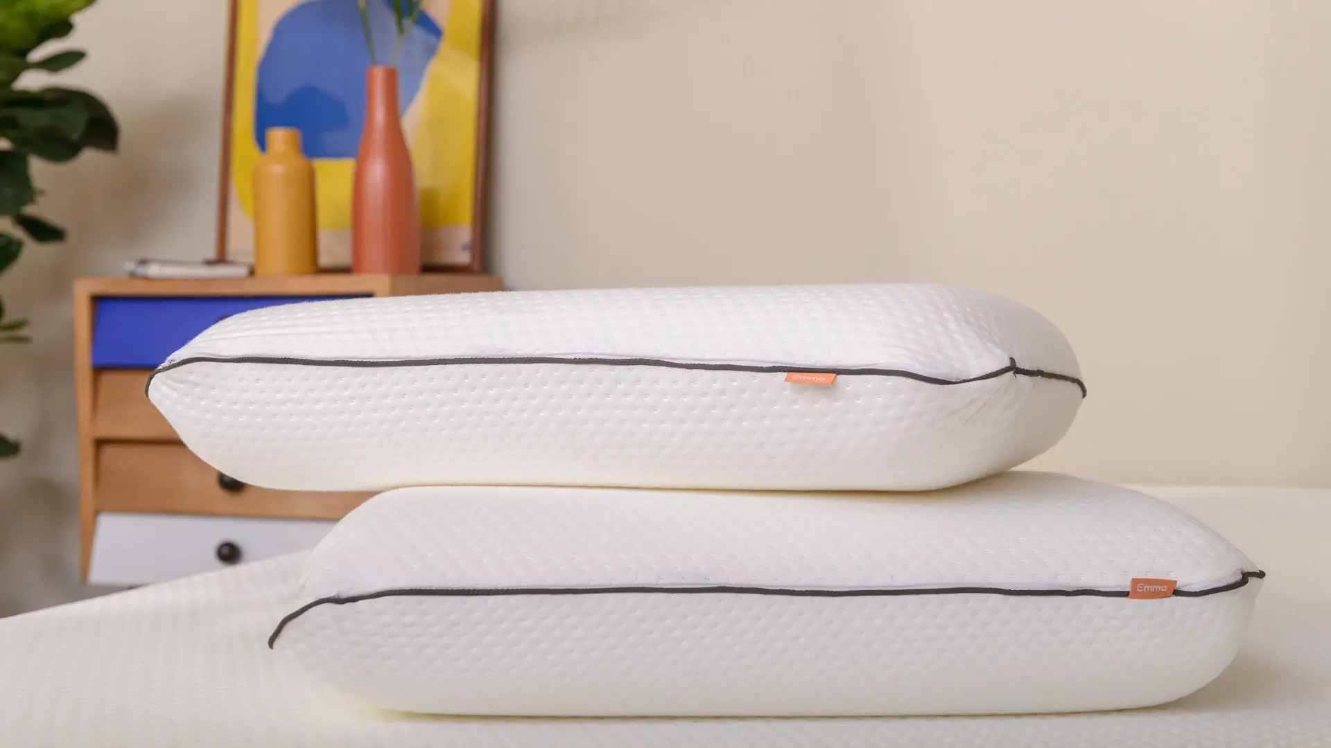 Dois colchões brancos sobrepostos em cima de uma cama. Escrivaninha ao fundo.