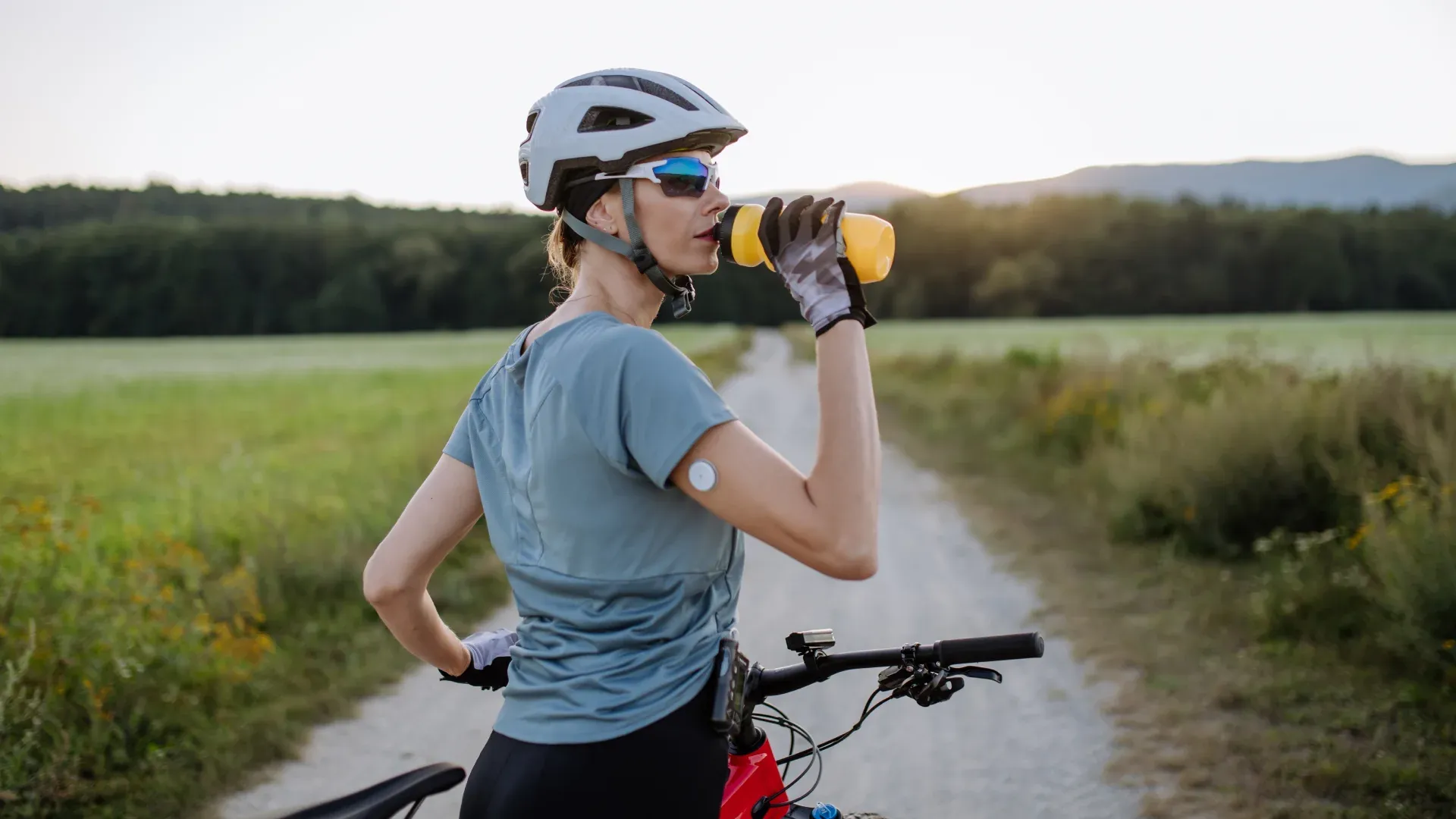 Mulher em bicicleta bebendo água em sua garrafinha