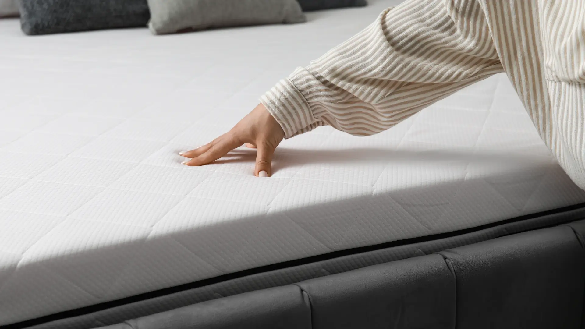 Pessoa com mão apoiada em colchão branco. 