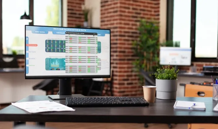 Monitor ligado mostrando gráficos sobre mesa de escritório