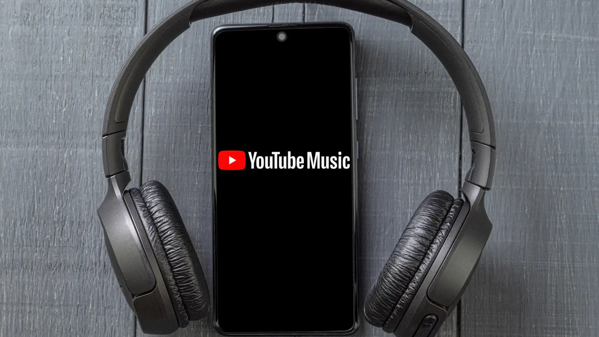Imagem de um celular com o papel de parede do Youtube Music e um headphone