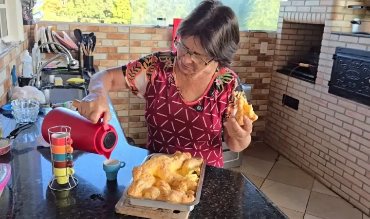 Print do vídeo da Dona Vera Lúcia, dona da receita de biscoito montanha-russa, experimentando o biscoito e servindo um café.