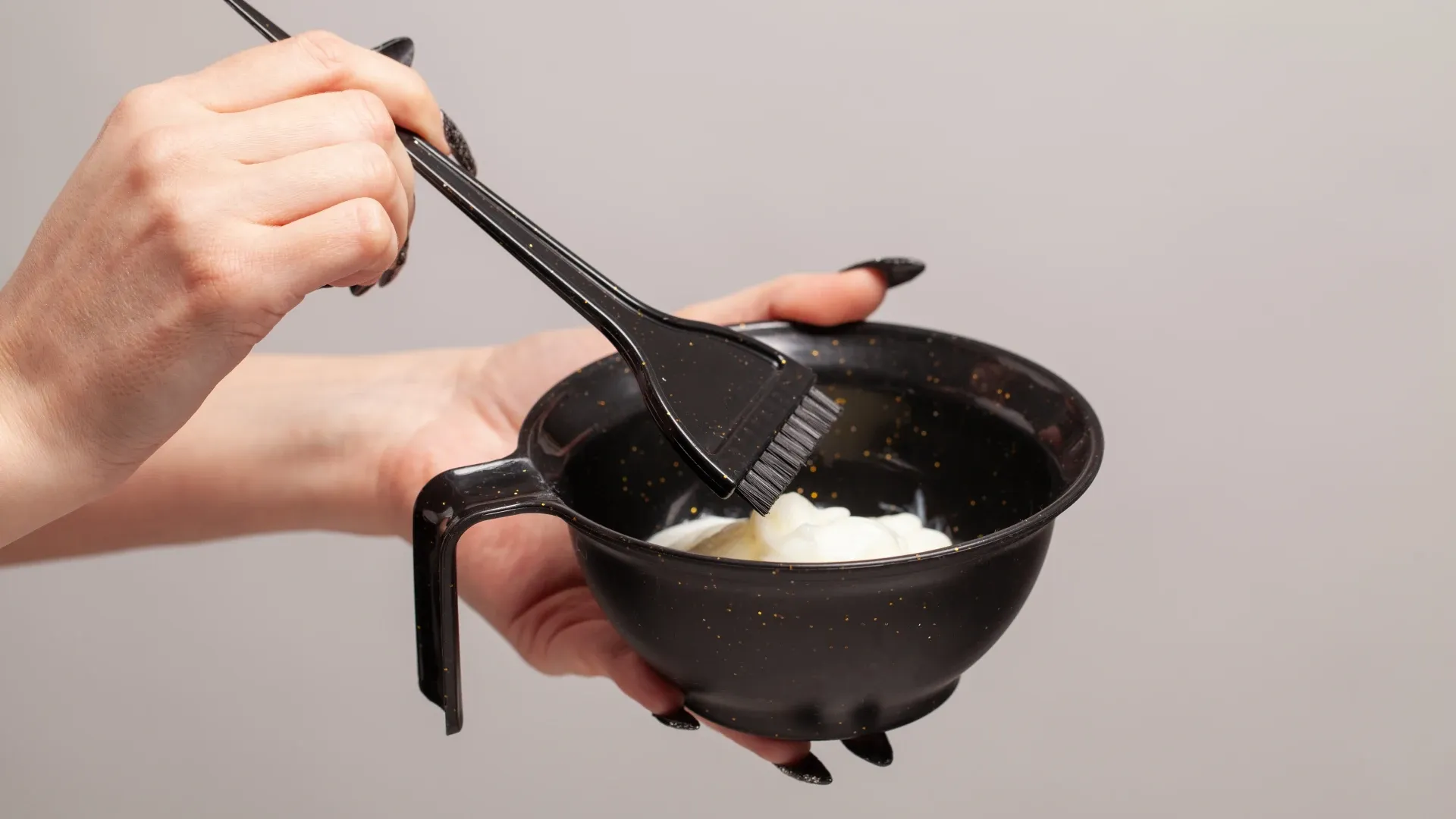 Mulher misturando tonalizante e outros produtos para cabelo em um pote