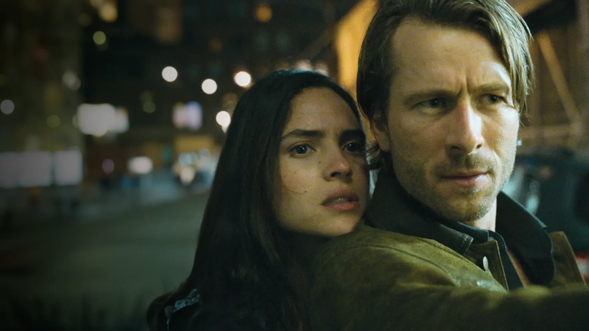 Casal com rostos pertos um do outro enquanto encaram algo tensos