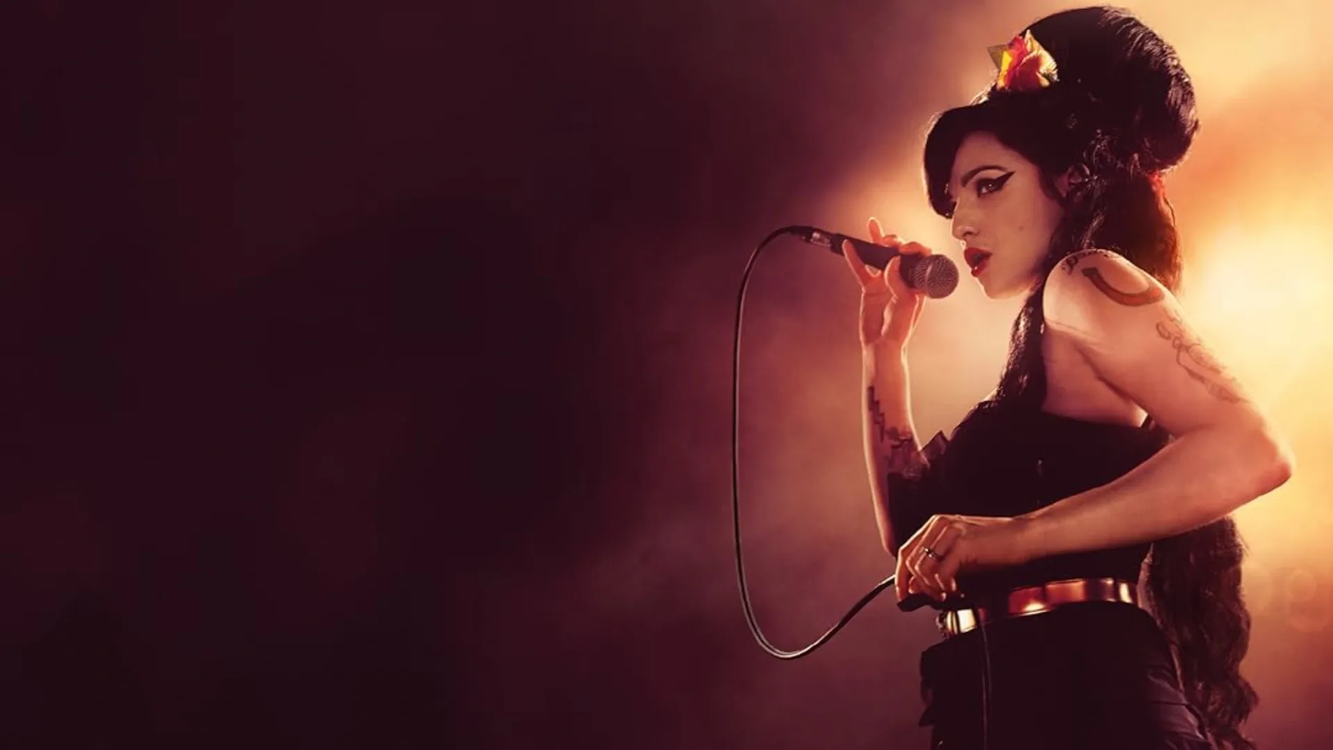 A atriz que interpreta a cantora Amy Winehouse enquanto canta com um fundo vinho e laranja