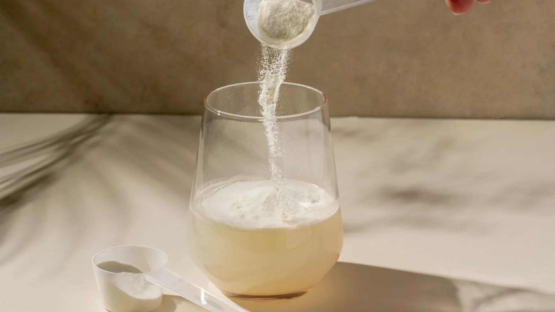 Scoop com creatina sendo colocado em um copo com água