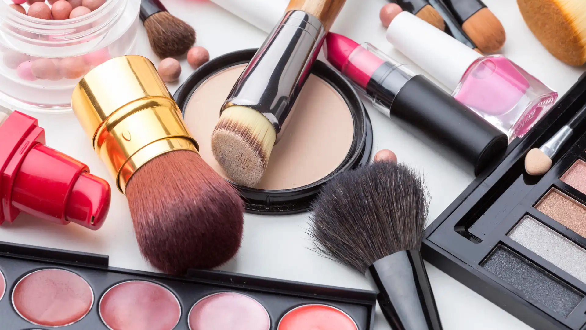 Produtos e pinceis de maquiagem em uma mesa branca