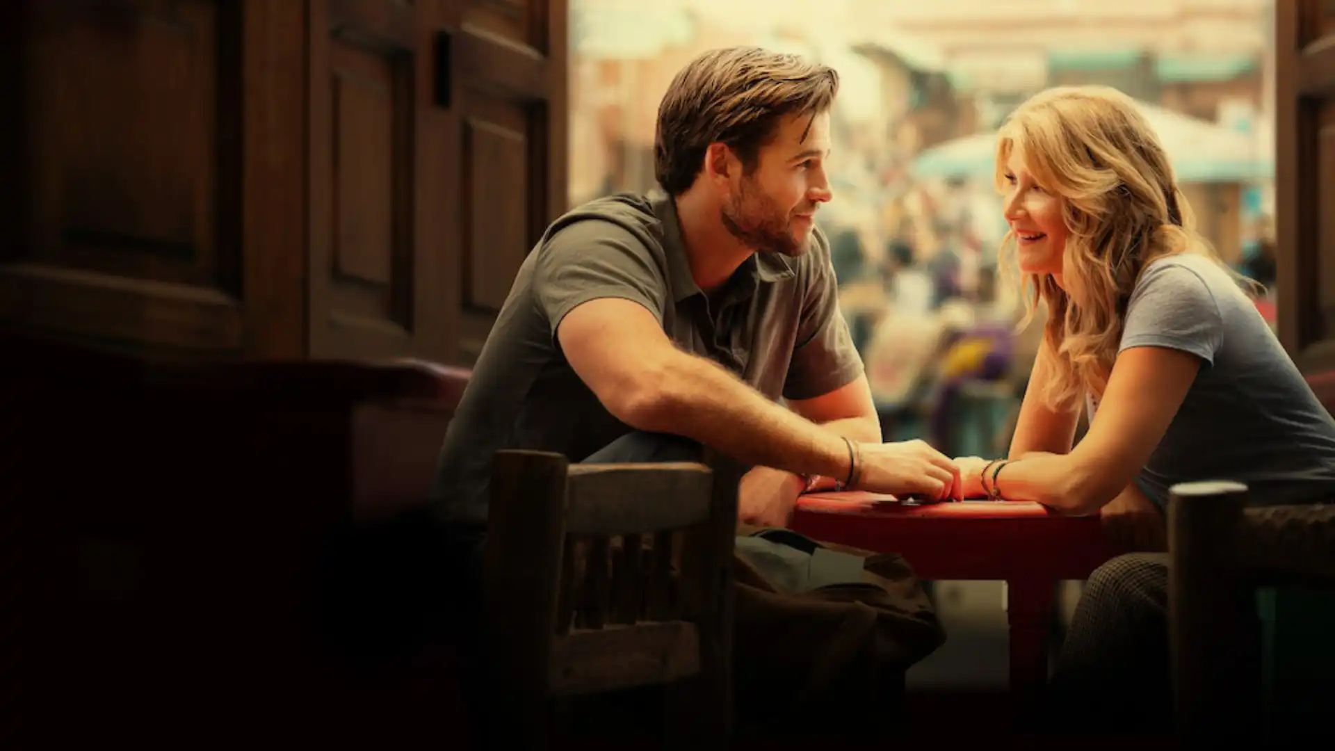 Casal segurando a mão um do outro enquanto se encaram em um restaurante em um fundo escuro.