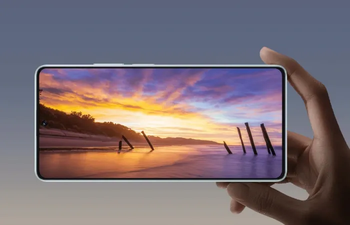 Imagem de uma mão segurando o celular Poco F5 na horizontal com a tela ligada