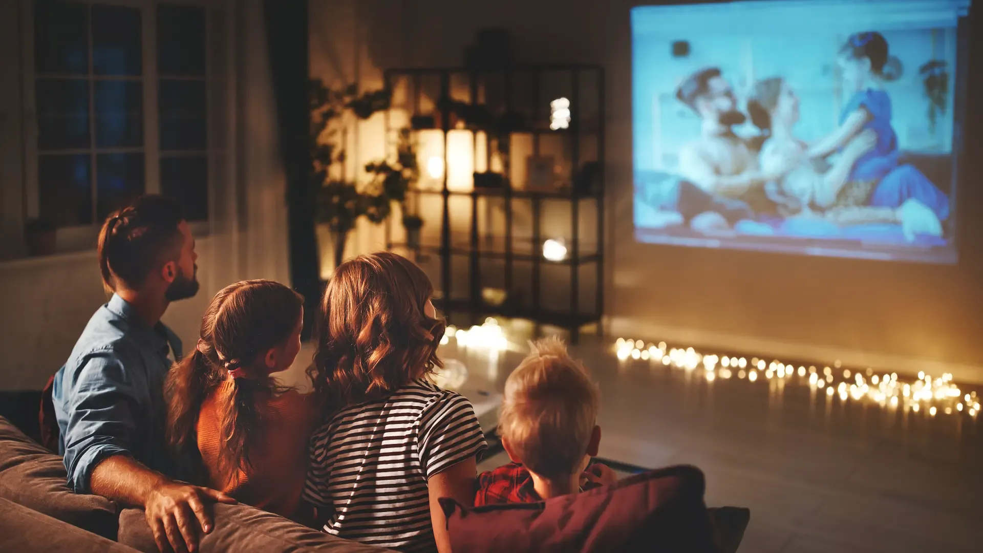 Família assistindo filmes em uma tela com projetor sendo usado